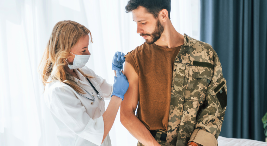 A woman gives medication to a military veteran, highlighting the importance of ongoing care for service-connected conditions like Fournier’s gangrene. Consistent treatment and support are essential for managing complications and maintaining quality of life.