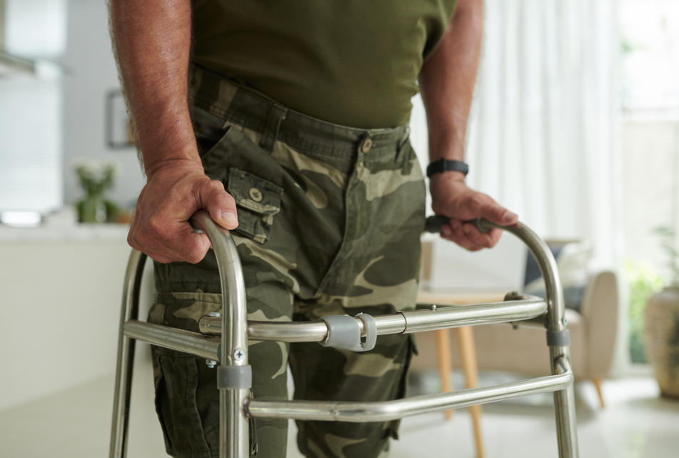 Veteran using a walker due to severe shin splints, a condition causing lower leg pain and mobility issues.